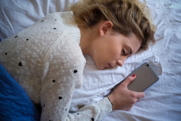 Dievča spí s mobilom v posteli