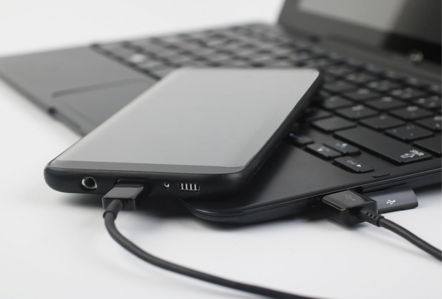 Smartphone pripojený k notebooku cez USB kábel.